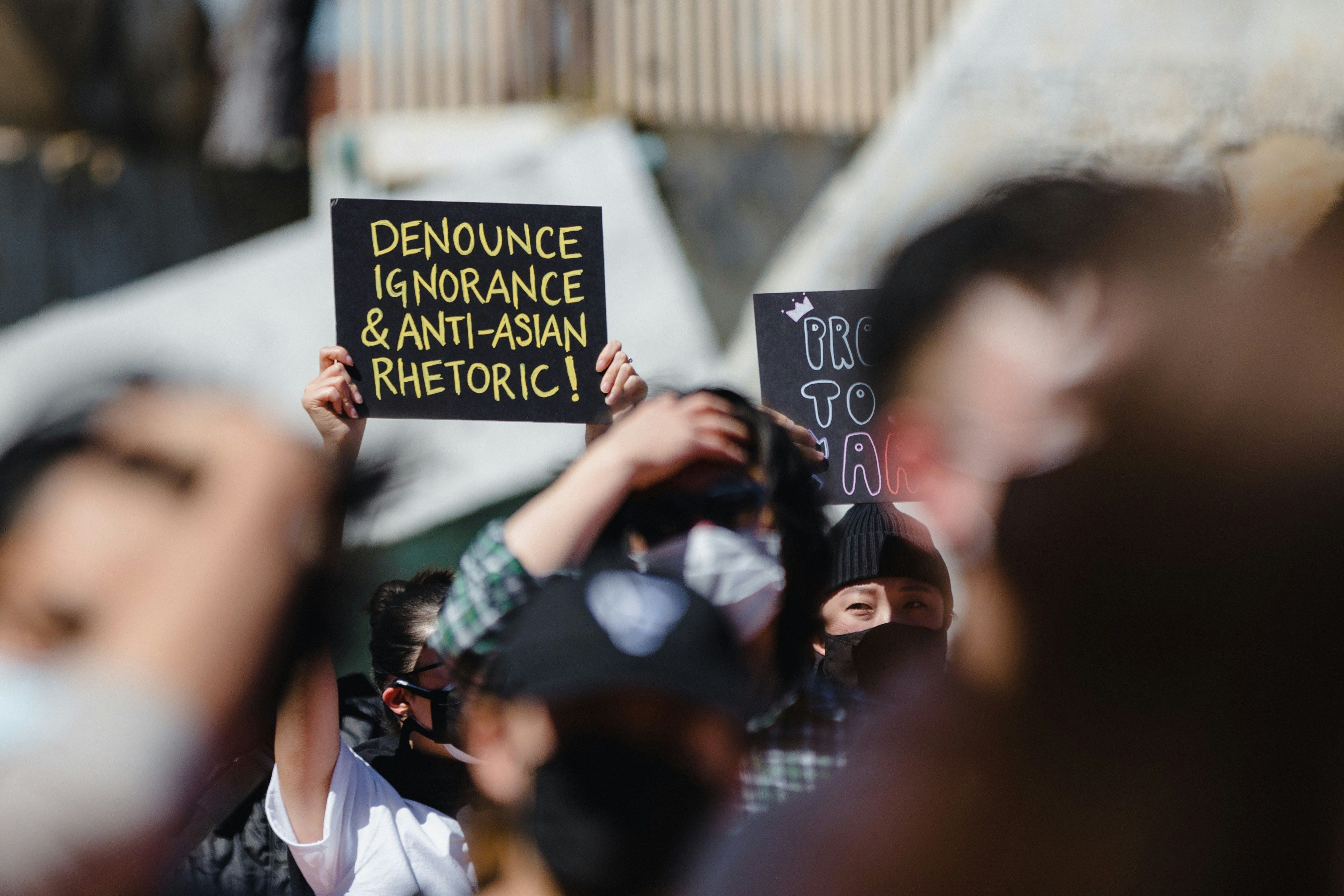 An activist holds a sign reading 'Denounce ignorance & anti-Asian rhetoric